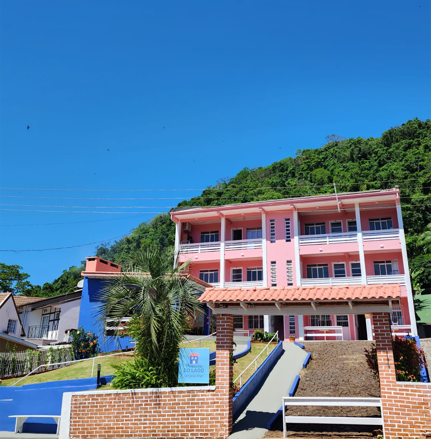 Fachada e entrada da Pousada do Lago sob o céu azul